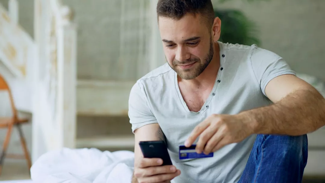 Man using phone and credit card for online shopping.