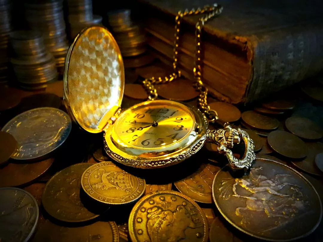 Antique pocket watch surrounded by old coins