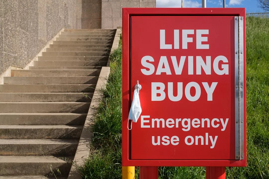 a red life saving buoy sign sitting on the side of a building